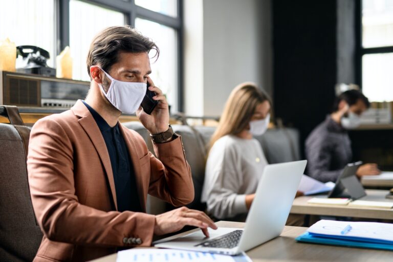 Portrait of young businesspeople with face masks working indoors in office