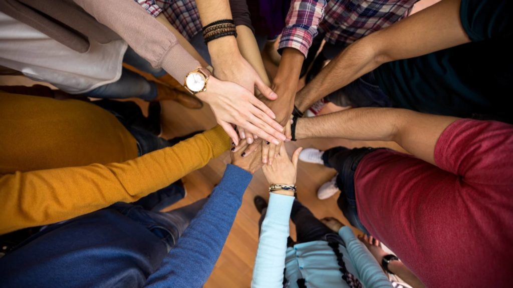 Diverse Group of People with Hands Meeting in Center of Group in Teamwork